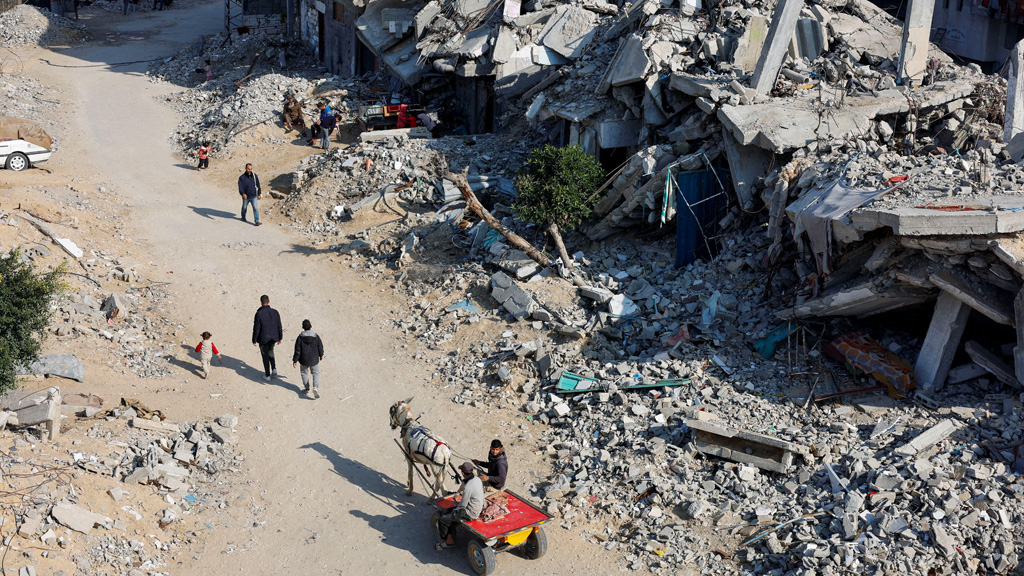 Palestinians ride a donkey-drawn cart as others walk past the rubble of houses, destroyed in previous Israeli strikes, amid the Israel-Hamas conflict, in Khan Younis, southern Gaza Strip, Jan 7, 2025. REUTERS/Mohammed Salem